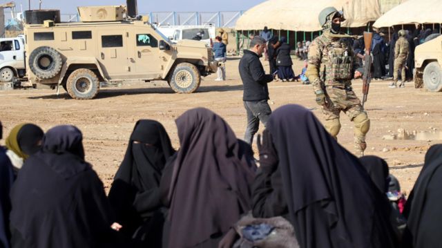 Mulheres com burka em frente a um soldado