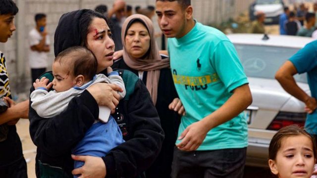 Una mujer con un bebé en brazos huyendo con otros civiles