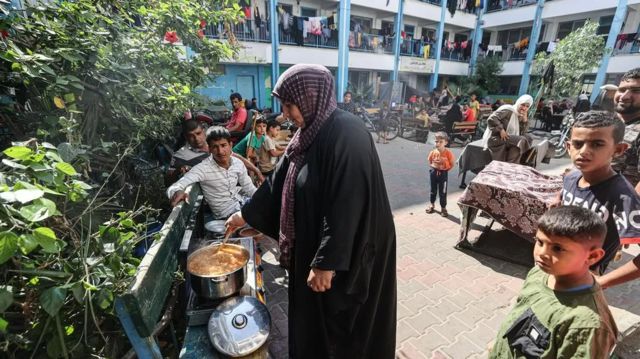 স্কুলে আশ্রিত মানুষেরা বাইরের আঙিনায় রান্না করছেন।