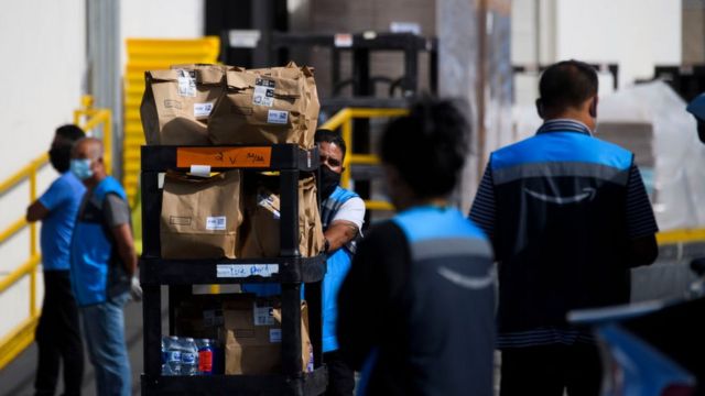 Funcionários da Amazon carregando caixas