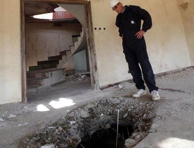 Former Serbia and Montenegro army officer Martin Martinovic stands between two holes in roof and floor of Chinese ambassy in Belgrade, Friday, 18June 2004.