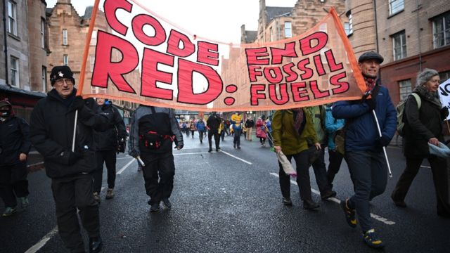 Manifestantes en Glasgow con un cartel que dice: "Alerta roja, fin a los combustibles fósiles"