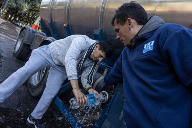 Un hombre rellena una botella de plástico de un camión con agua potable en Montevideo.