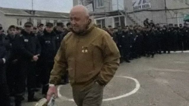 Yevgeny Prigozhin caminhando em frente a prisioneiros em pé lado a lado