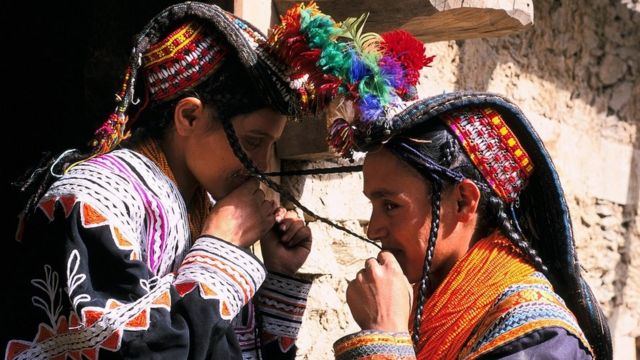 Geleneksel kıyafetleriyle Kalaş kızlar birbirinin örgülerini öpüyor