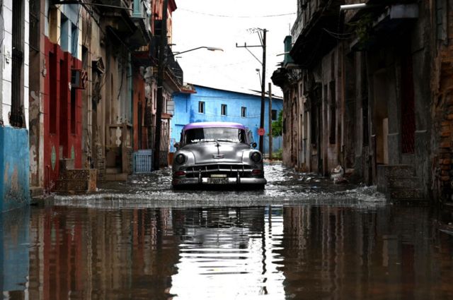 Un coche viejo circula por una calle inundada en La Habana.