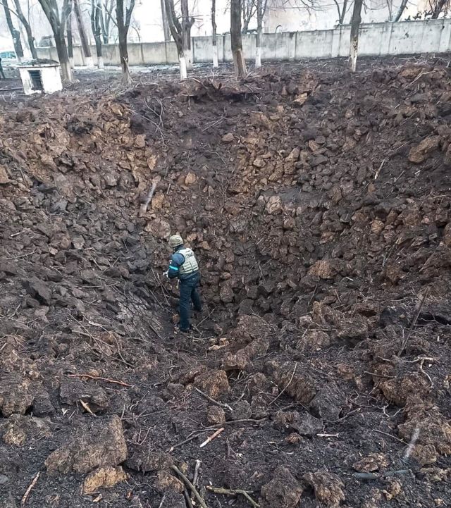 Membro dos serviços de emergência ucranianos examina uma grande cratera de bomba em hospital infantil e maternidade em Mariupol