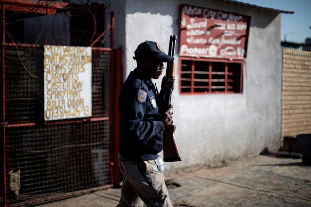 A South African police officer holds a rifle as he stands in Soweto