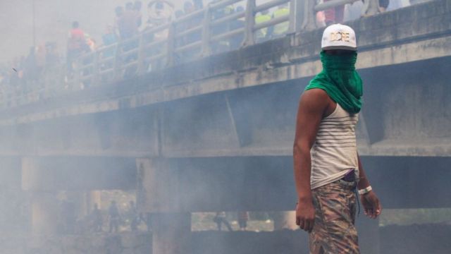 Manifestante con la cara tapada en medio de gases