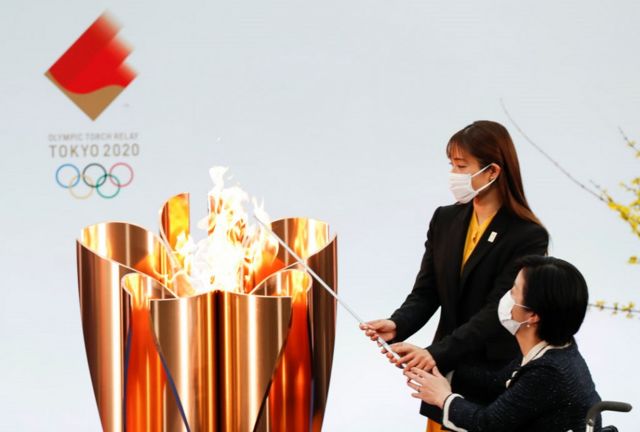 谁将点燃圣火通常是奥运会开幕式上最大的悬念。图为今年3月25日，日本运动员田口亚希和艺人石原里美（又译石原聪美）点燃东京奥运传递火炬台。(photo:BBC)