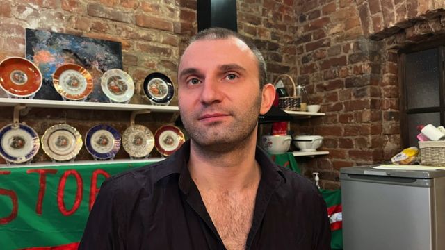 Piotr Voznesensky em frente a prateleiras de pratos ornamentais