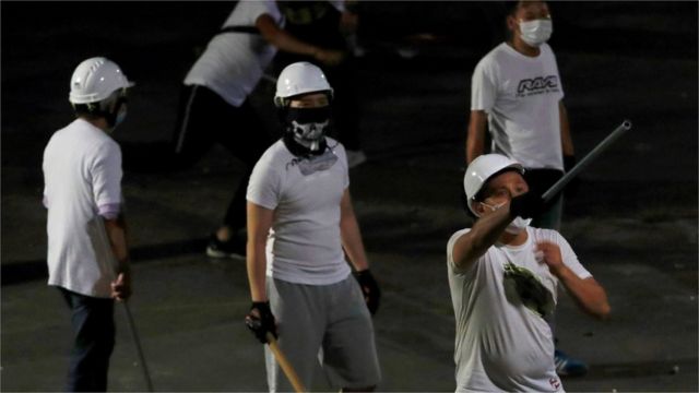 Men in white T-shirts with poles are seen in Yuen Long after attacked anti-extradition bill demonstrators at a train station, in Hong Kong