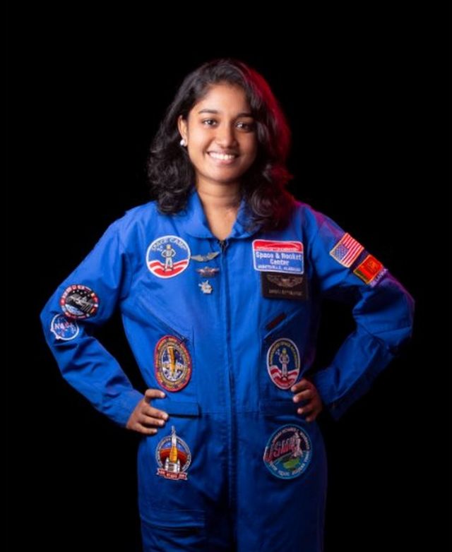Sandali Kumarasinghe wearing a space uniform and smiling while posing for a photo