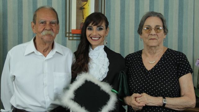 Paola (ao centro) posa ao lado dos pais