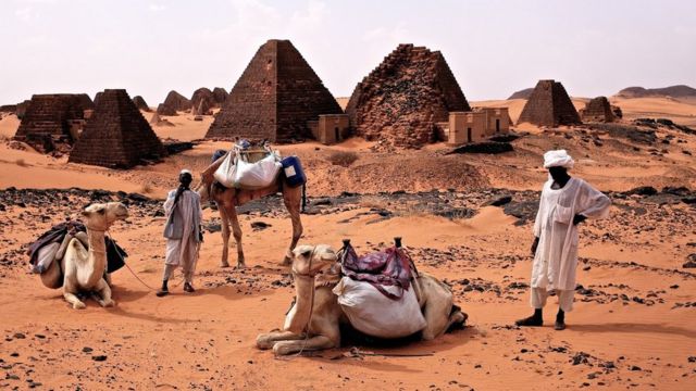 Camels and porters in the Sahara desert