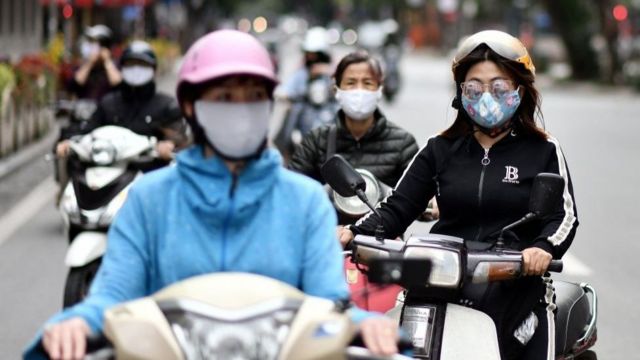 Vietnamese women wearing masks ride motorcycles