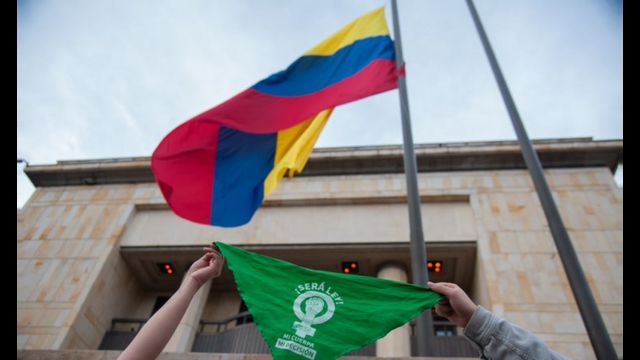 Bandana verde abaixo de bandeira colombiana em frente ao Tribunal Constitucional da Colômbia