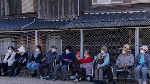 Uma idosa usa seu telefone para tirar fotos enquanto assiste a 'Sisimai', uma dança tradicional japonesa realizada por Ise Daikagura em 13 de outubro de 2022 em Inujima, Japão.