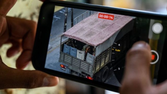 A person holds a mobile phone showing a video of soldiers looking out from a truck in Yangon on February 28, 2021, as security forces continue to crackdown on demonstrations by protesters against the military coup