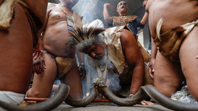 Supporters of King Khoisan South Africa burn incense and chant slogans outside the Pretoria Magistrates Court while waiting for his release from police custody following his arrest for planting marijuana at the Union Buildings in Pretoria on January 13, 2022.