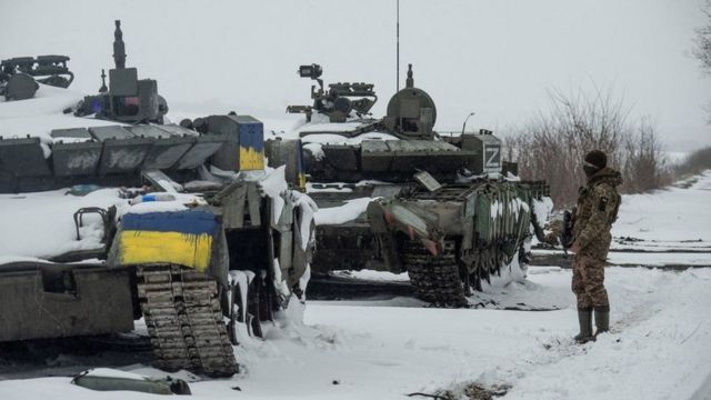 A Ukrainian serviceman stands near captured Russian tanks in the north of the Kharkiv region