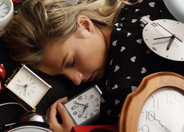 Una donna addormentata circondata da orologi