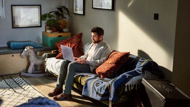 Hombre sentado con una laptop en un sofá