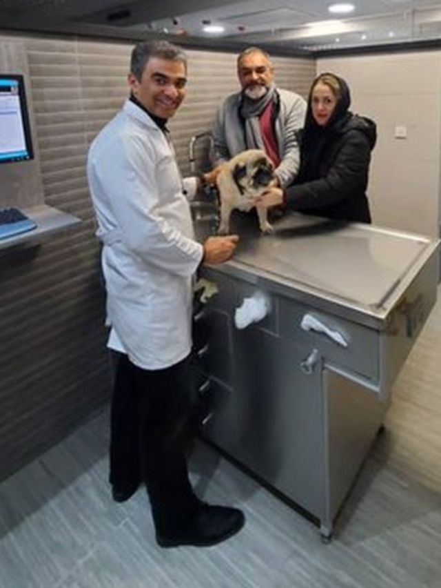 Dr Mohebi em sua clínica com um cachorro e um casal