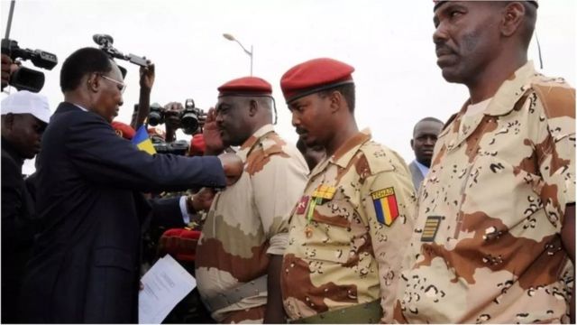 e président tchadien Idriss Deby Itno (G) décore le général du contingent tchadien au Mali Oumar Bikimo (G) et le commandant en second Mahamat Idriss Déby Itno, son fils (C) lors de la cérémonie de bienvenue. Ndjamena, le 13 mai 2013. AFP PHOTO / STR