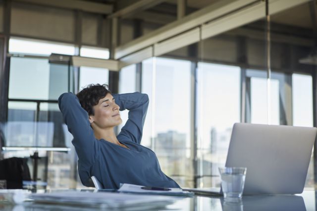Mulher sentada relaxada em frente a laptop no escritório