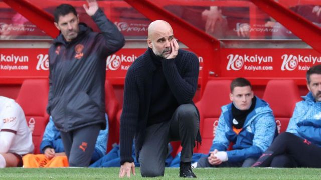 Pep Guardiola crouches on the sideline against Nottingham Forest