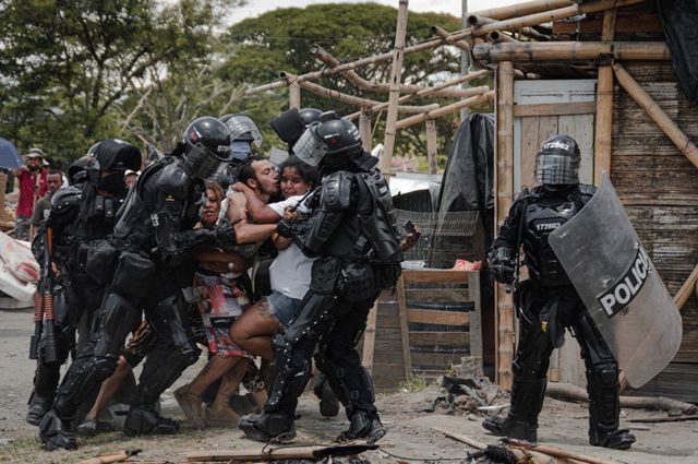 Agentes policiales arrestan a un hombre mientras su esposa y su familia resisten, durante los desalojos de personas del asentamiento San Isidro, en Puerto Caldas, Risaralda, Colombia, el 6 de marzo de 2021.