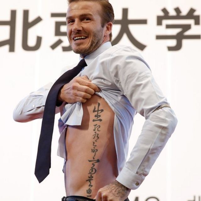 David Beckham muestra su tatuaje de letras chinas en un lado de su torso.