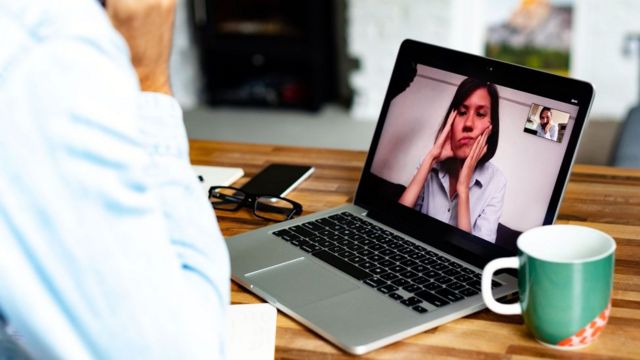 Mulher participando de videoconferência aparentando estar entediada