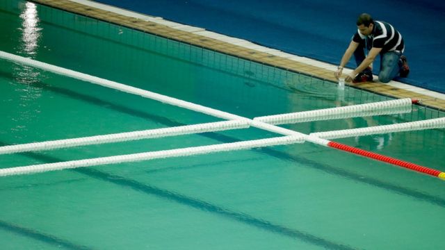 Técnico retira amostra da piscina do Centro Aquático, cuja água esverdeou