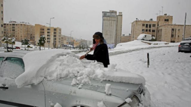 رجل يزيل الثلوج عن سيارته في العاصمة الأردنية عمان غداة عاصفة ثلجية ضربت البلاد