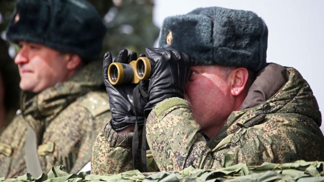 Russian solider looks through a pair of binoculars