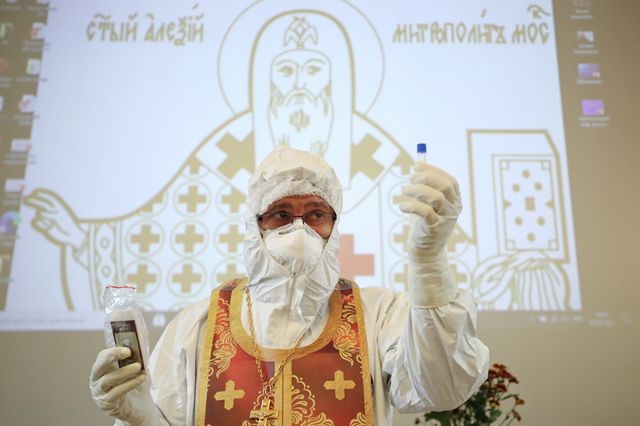 Протоиерей Иоанн Кудрявцев демонстрирует одноразовую пробирку с маслом для помазания