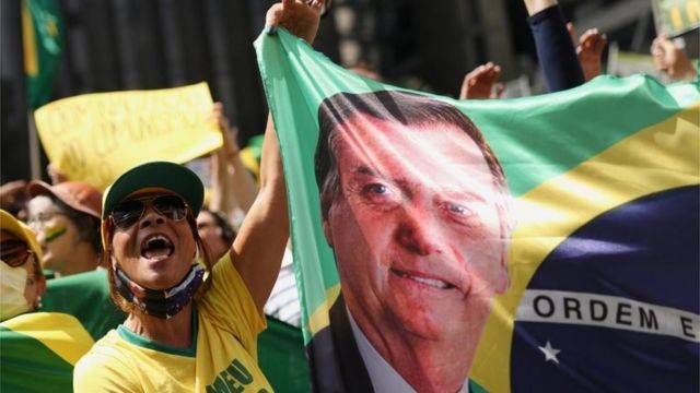 Apoiadora de Bolsonaro com bandeira do Brasil com rosto do presidente estampado