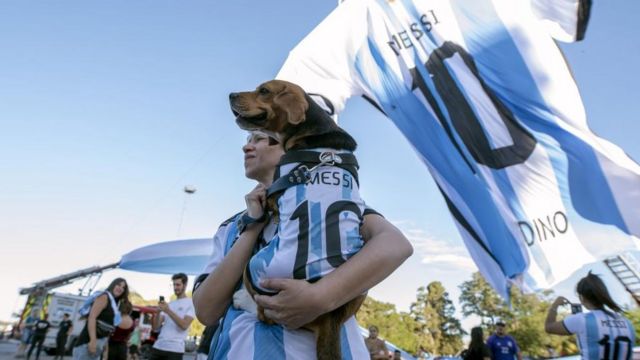 An Argentina fan holds a dog wearing a jersey with the number of Argentinian footballer Lionel Messi at the National Flag Monument on the eve of the final match of the FIFA World Cup 2022, in Rosario, Argentina, 17 December 2022.