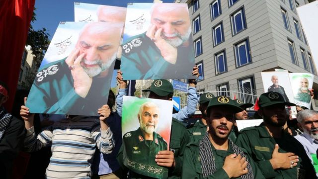 Iranian men, including members of the Revolutionary Guards, hold portraits during the funeral of Brigadier General Hossein Hamedani in Tehran on 11 October 2015