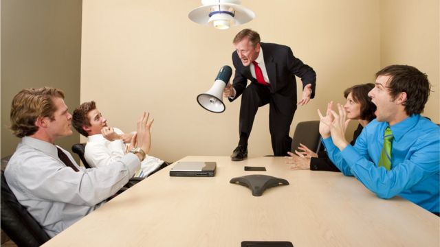 Imagen de un jefe que le grita a sus empleados con un megáfono.