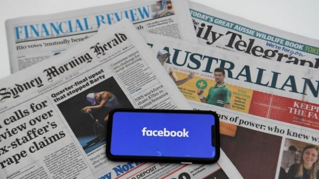 Un celular con el logo de Facebook sobre periódicos australianos