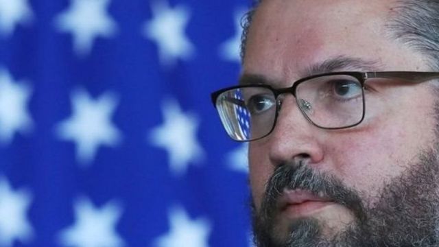 Ernesto Araújo de perfil, com bandeira atrás