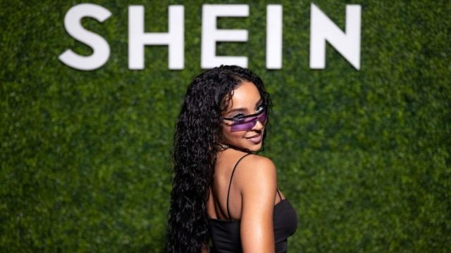 La cantante Tinashe posa frente a un logo de Shein.