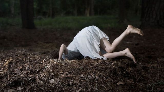 Menina com cabeça dentro de buraco