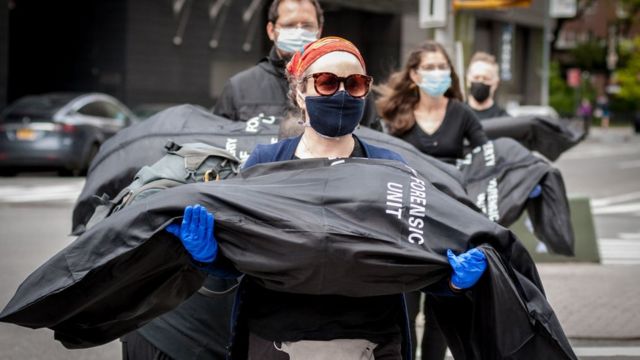 Activists from "Rise and Resist" and "Indivisible Brooklyn" carry body bags symbolizing the victims who so far have died due to complications of the COVID-19 virus in the US