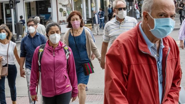 People with a mask walk down the street