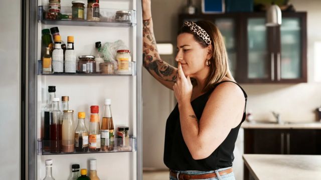 Woman looking at the fridge with a look of indecision
