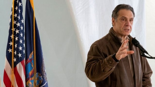 Cuomo speaks on the platform, with flags behind